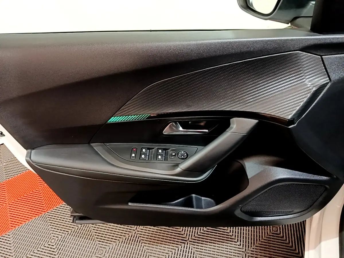 Détail de la porte avant gauche du Peugeot 2008 blanc, avec insert décoratif noir et commandes électriques des vitres.