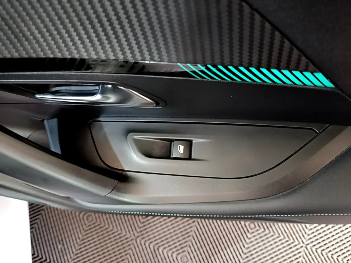 Détail de la porte intérieure côté gauche d’un Peugeot 2008 blanc, avec poignée argentée et bande décorative lumineuse bleue.
