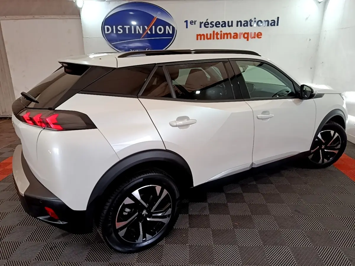 Vue 3/4 arrière droite du Peugeot 2008 blanc avec toit noir et feux arrière LED en forme de griffes.