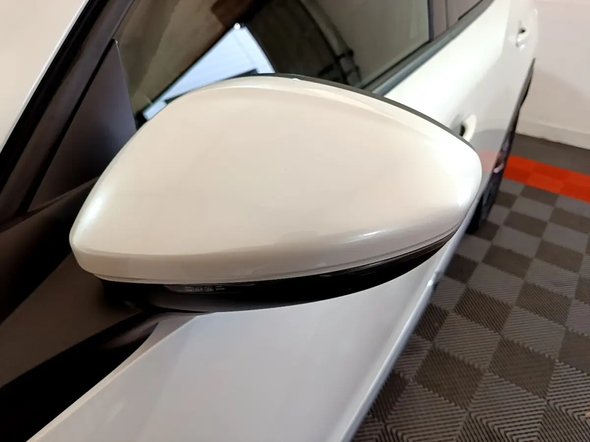 Rétroviseur droit blanc du Peugeot 2008 BlueHDi 130, vue rapprochée avec carrosserie et sol damier en arrière-plan.