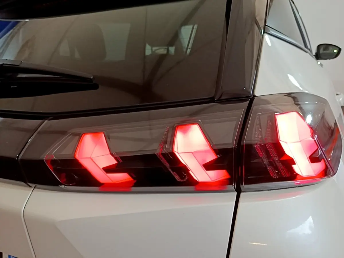 Gros plan sur le feu arrière droit rouge allumé d’un Peugeot 2008 blanc, vue arrière côté droit.