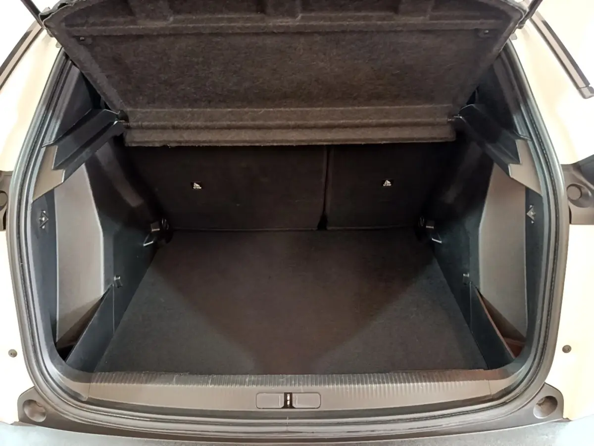 Coffre ouvert vu de face d’un Peugeot 2008 blanc, montrant l’espace de chargement vide et la tablette arrière relevée.