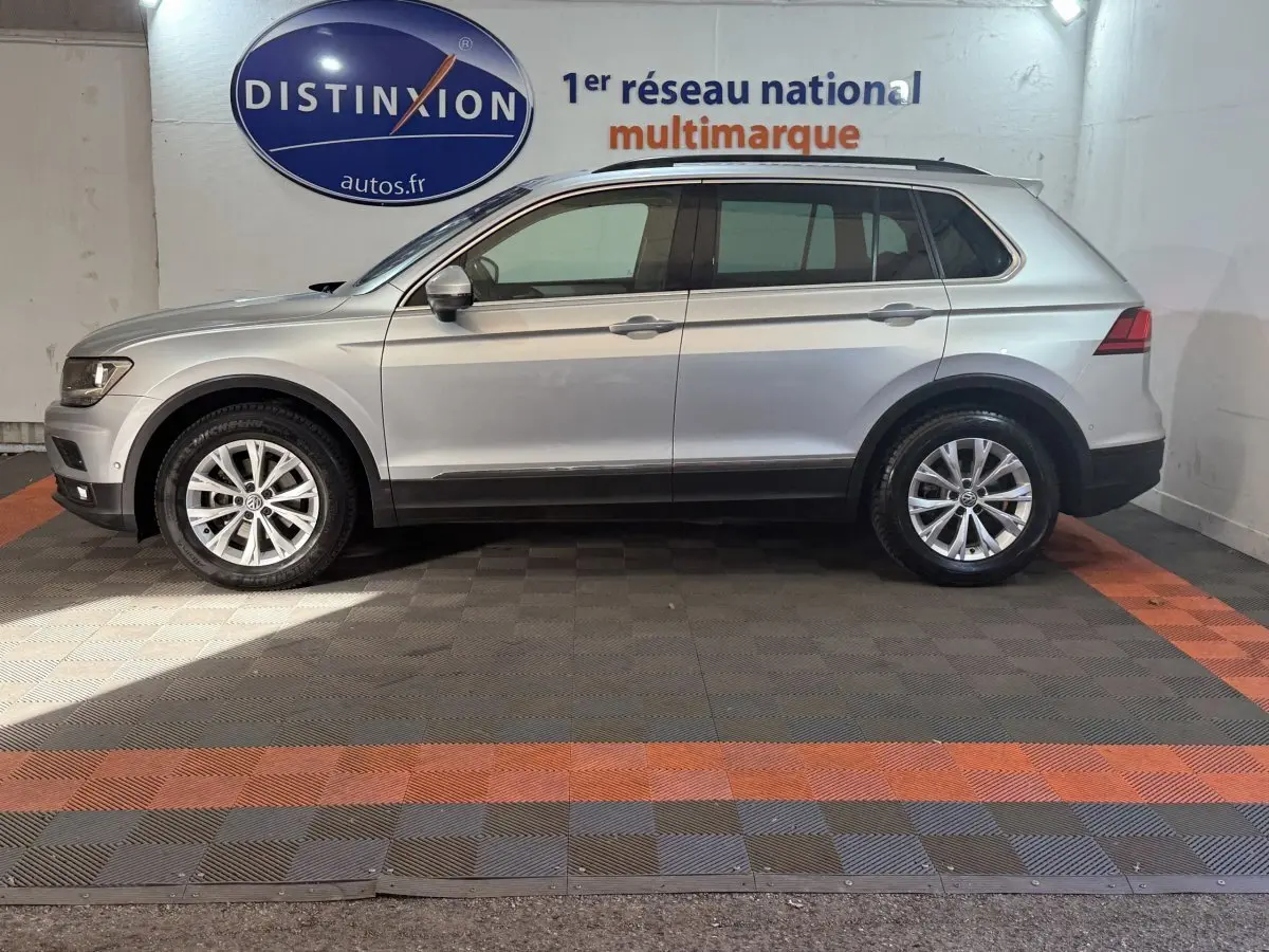 Profil droit d’un Volkswagen Tiguan gris clair 2020, SUV compact avec jantes alliage et barres de toit noires.