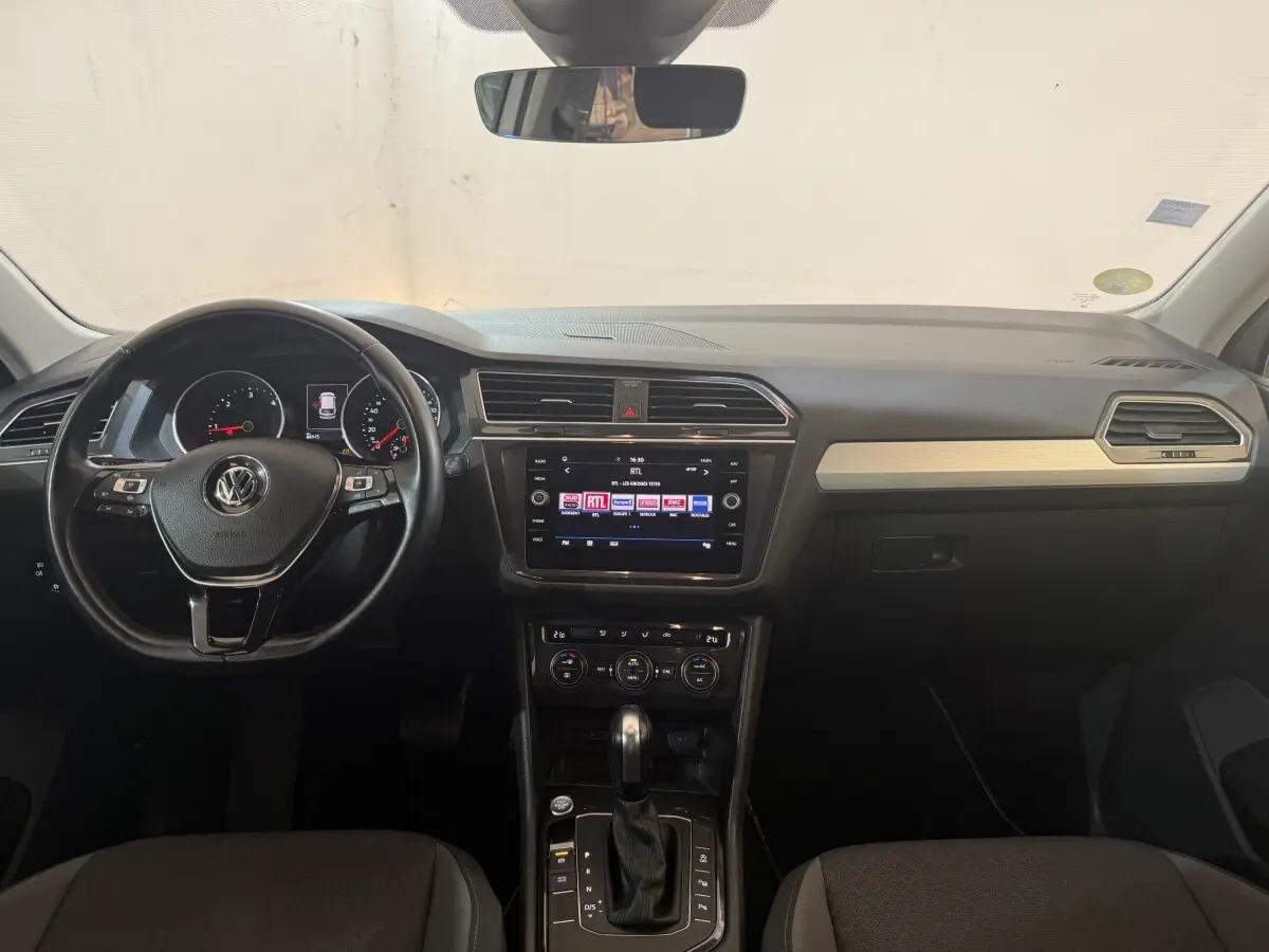 Vue intérieure avant du Volkswagen Tiguan 2020, tableau de bord noir avec écran tactile et volant cuir multifonctions.