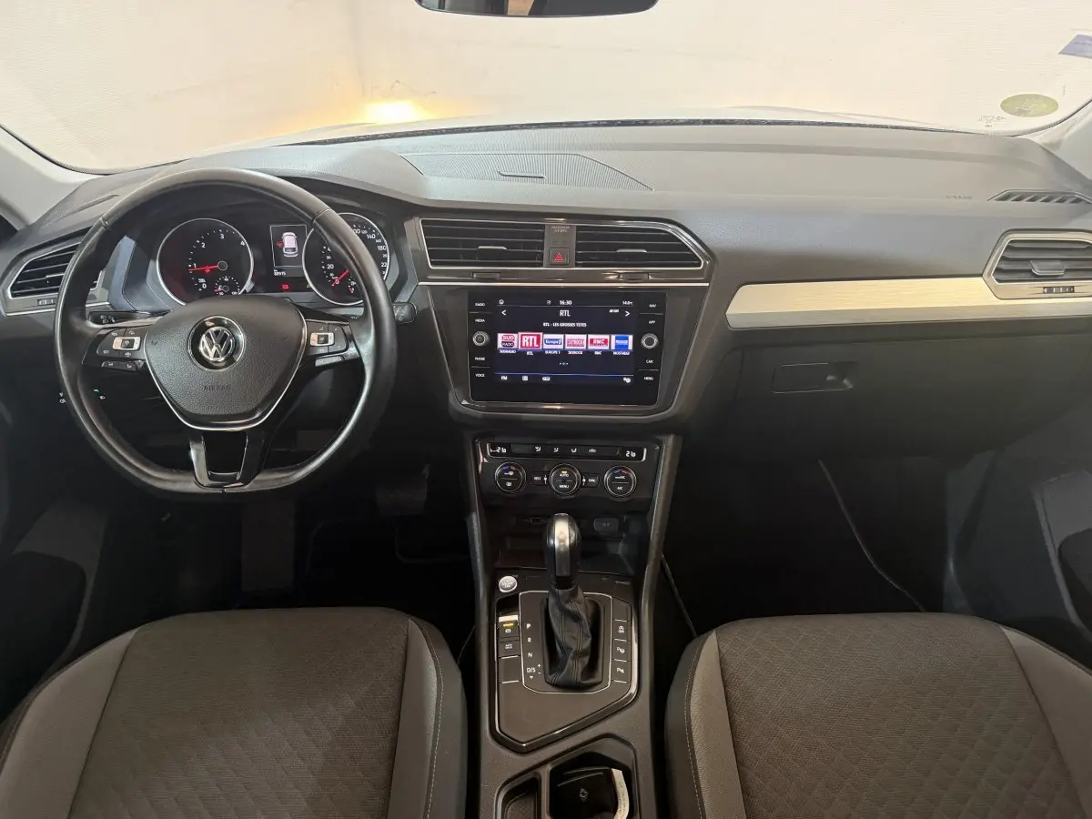 Vue intérieure avant du Volkswagen Tiguan 2020, tableau de bord avec volant cuir multifonctions et écran tactile central.