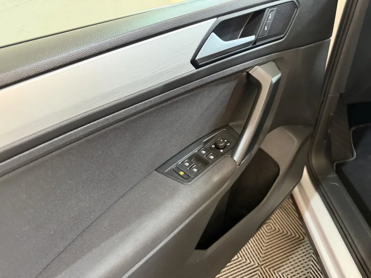 Vue rapprochée de la porte avant gauche du Volkswagen Tiguan 2020, avec commandes électriques et finition noire.