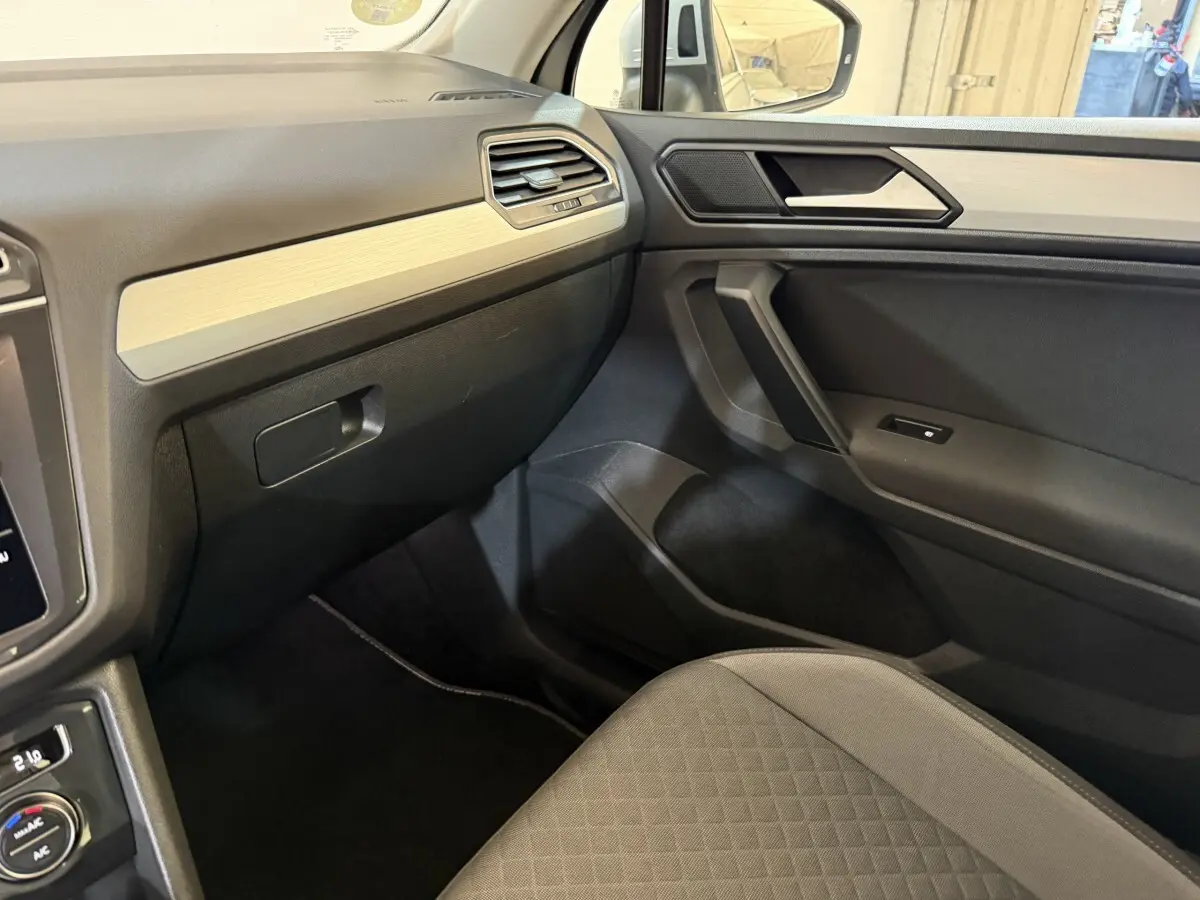 Vue intérieure côté passager du Volkswagen Tiguan 2020 gris clair, avec tableau de bord et garniture beige clair.