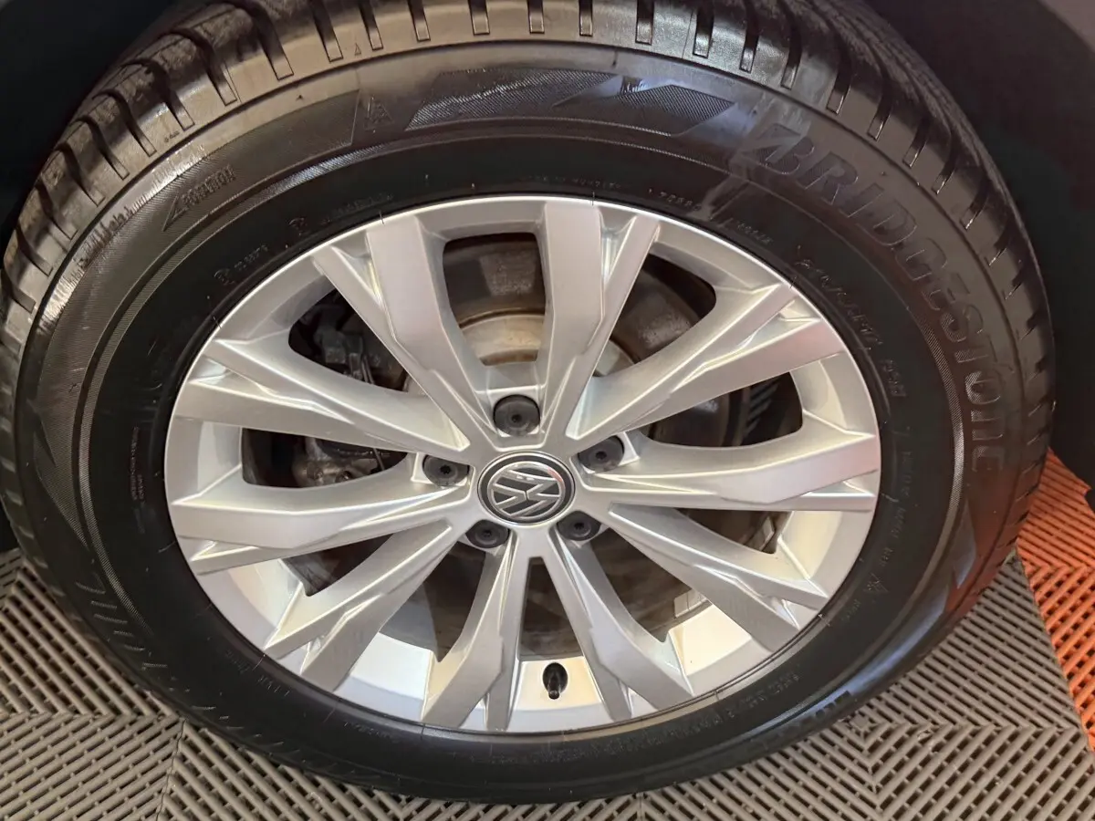 Gros plan sur la roue avant droite avec jante argentée et logo Volkswagen au centre, pneu Bridgestone noir.