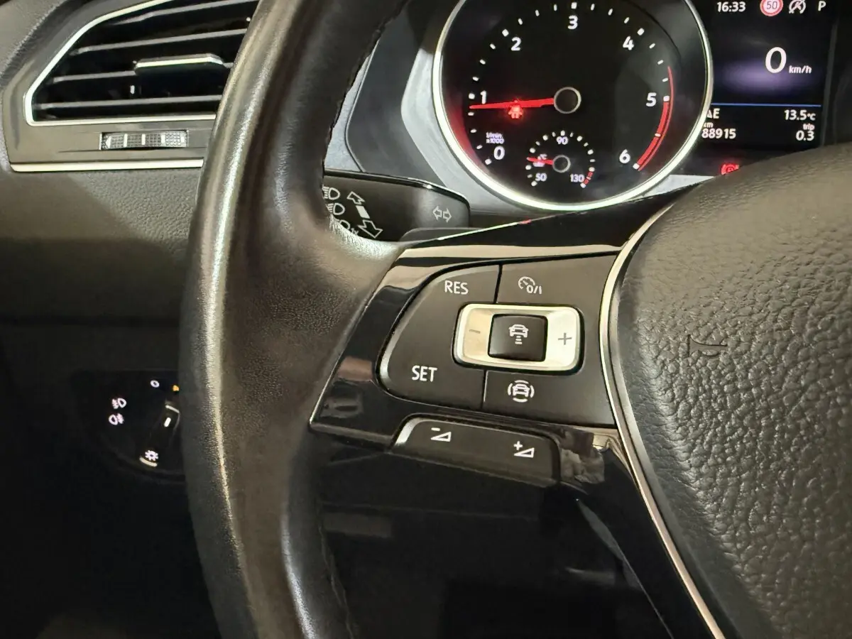 Gros plan sur le volant cuir multifonctions gris du Volkswagen Tiguan 2.0 TDI 150 DSG7 avec commandes de régulateur de vitesse.