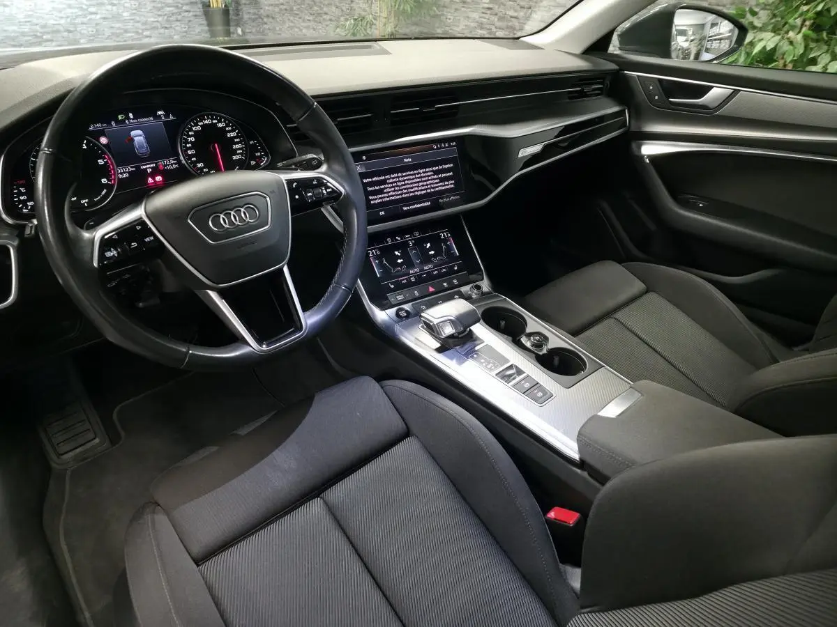 Vue intérieure côté conducteur de l'Audi A6 Avant 2022 avec tableau de bord numérique et sellerie noire.
