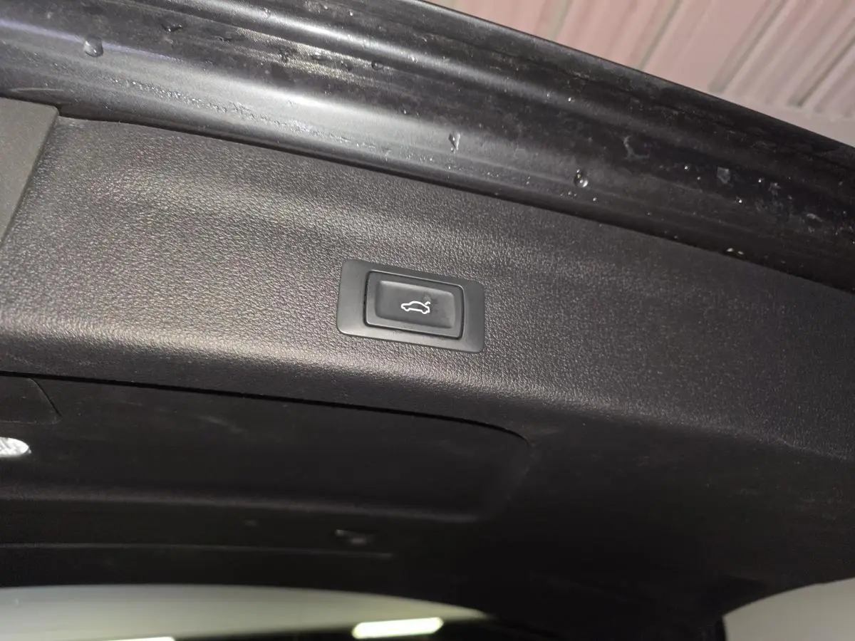 Bouton d'ouverture électrique du hayon sur la partie intérieure du coffre d'une Audi A6 gris 2022 S line.