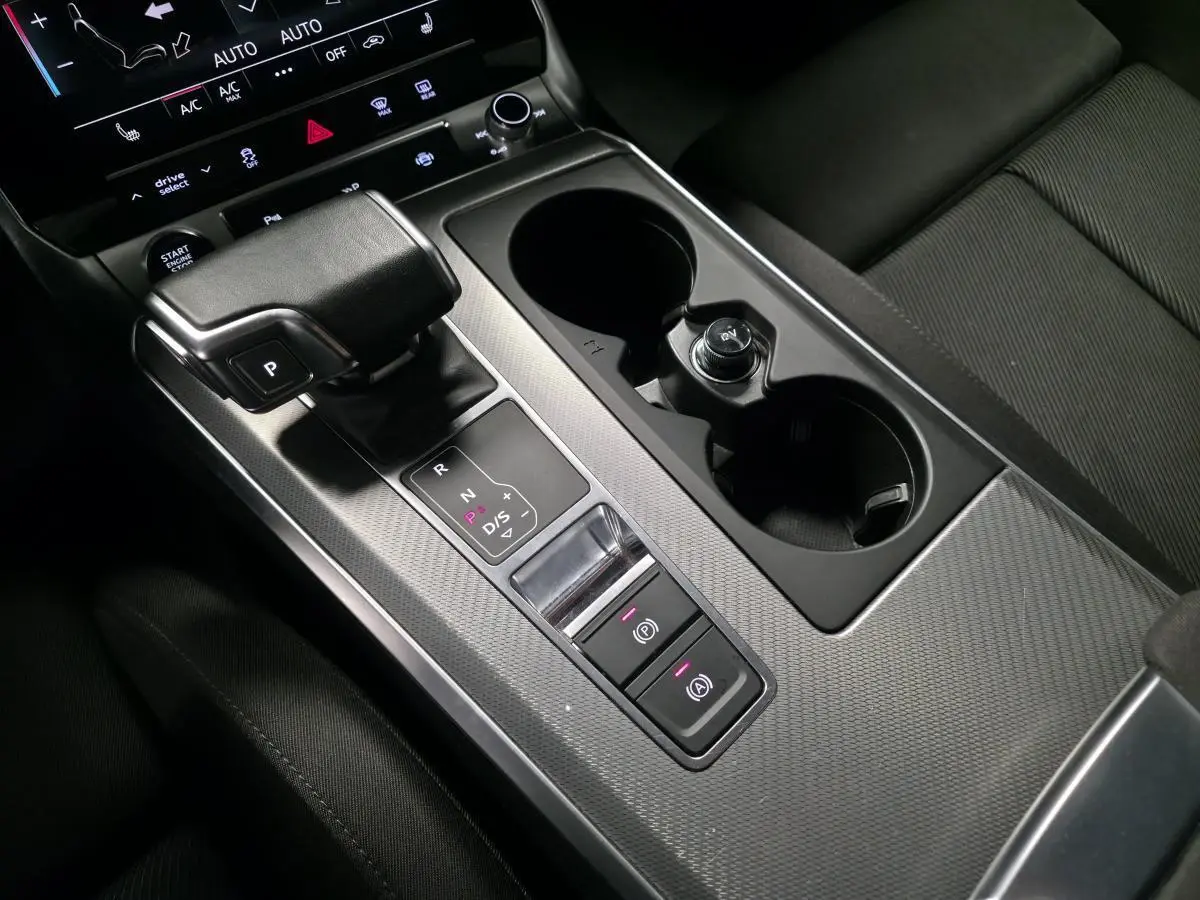 Gros plan sur la console centrale noire de l'Audi A6 Avant 2.0 TDI 2022 avec levier de vitesses et porte-gobelets.