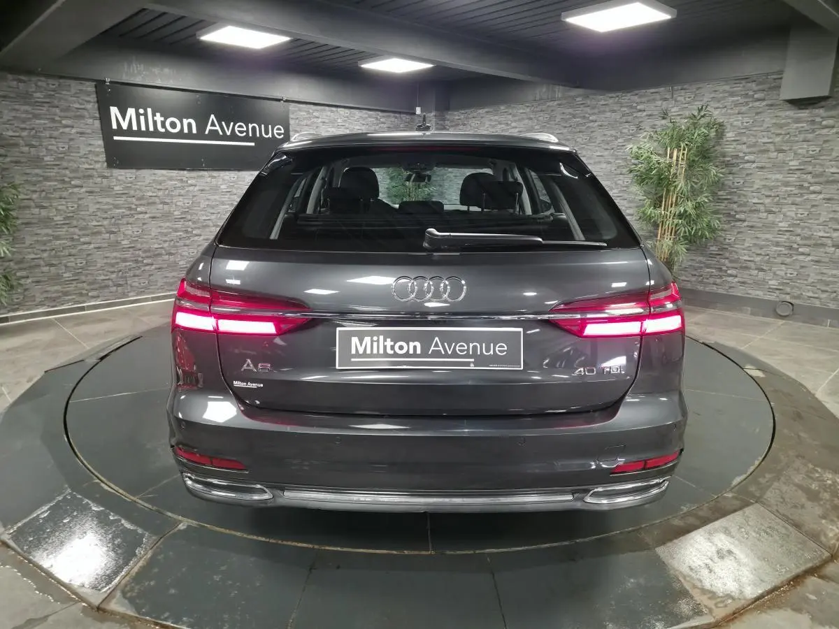 Vue arrière d'une Audi A6 Avant gris métallisé 40 TDI avec feux LED allumés dans un showroom.