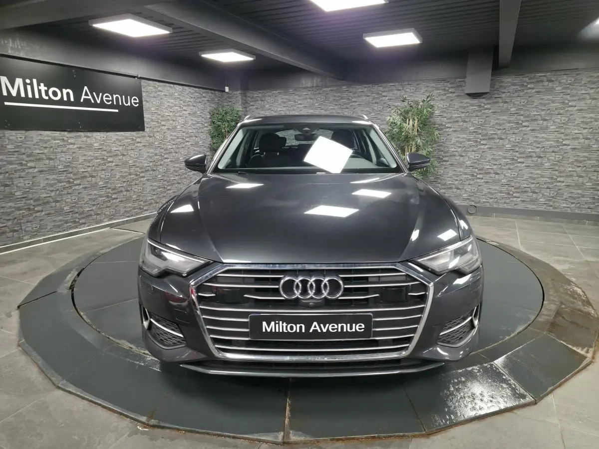 Audi A6 Avant gris vue de face dans un showroom avec calandre chromée et logo Audi visible.