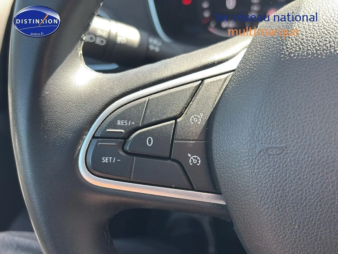 Gros plan sur les commandes de régulateur de vitesse au volant en similicuir noir de la Renault Mégane IV gris Highland.
