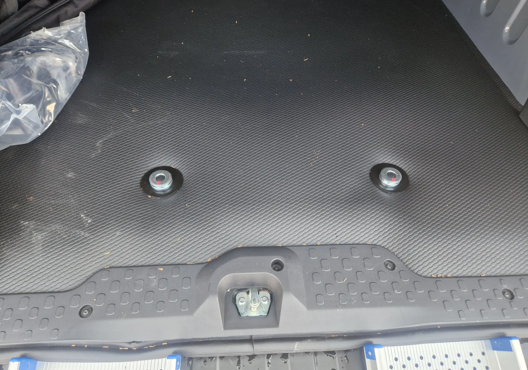 Vue rapprochée du plancher noir antidérapant du coffre du Renault Trafic Combi gris, avec deux plots de fixation pour fauteuil roulant.