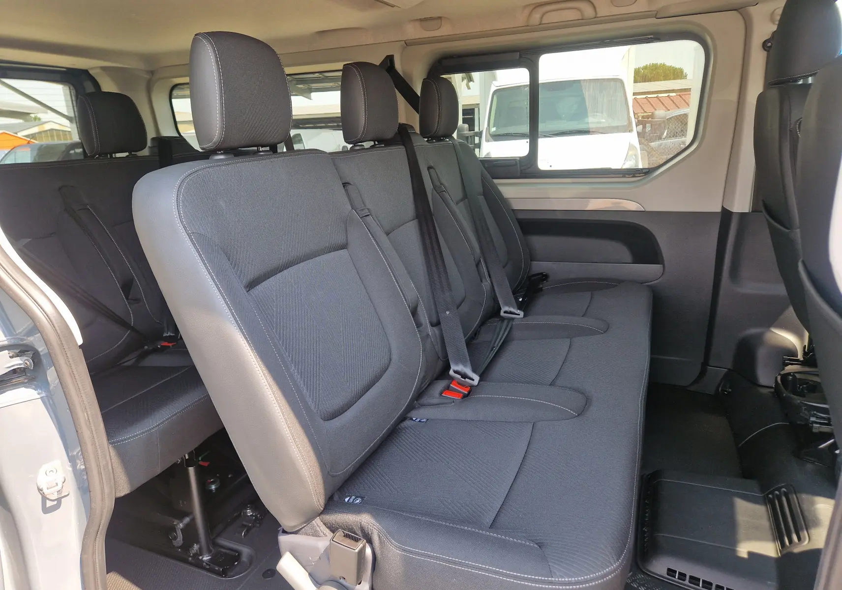Vue intérieure côté droit du Renault Trafic Combi 2026 gris urbain, montrant les sièges passagers en tissu noir avec ceintures de sécurité.