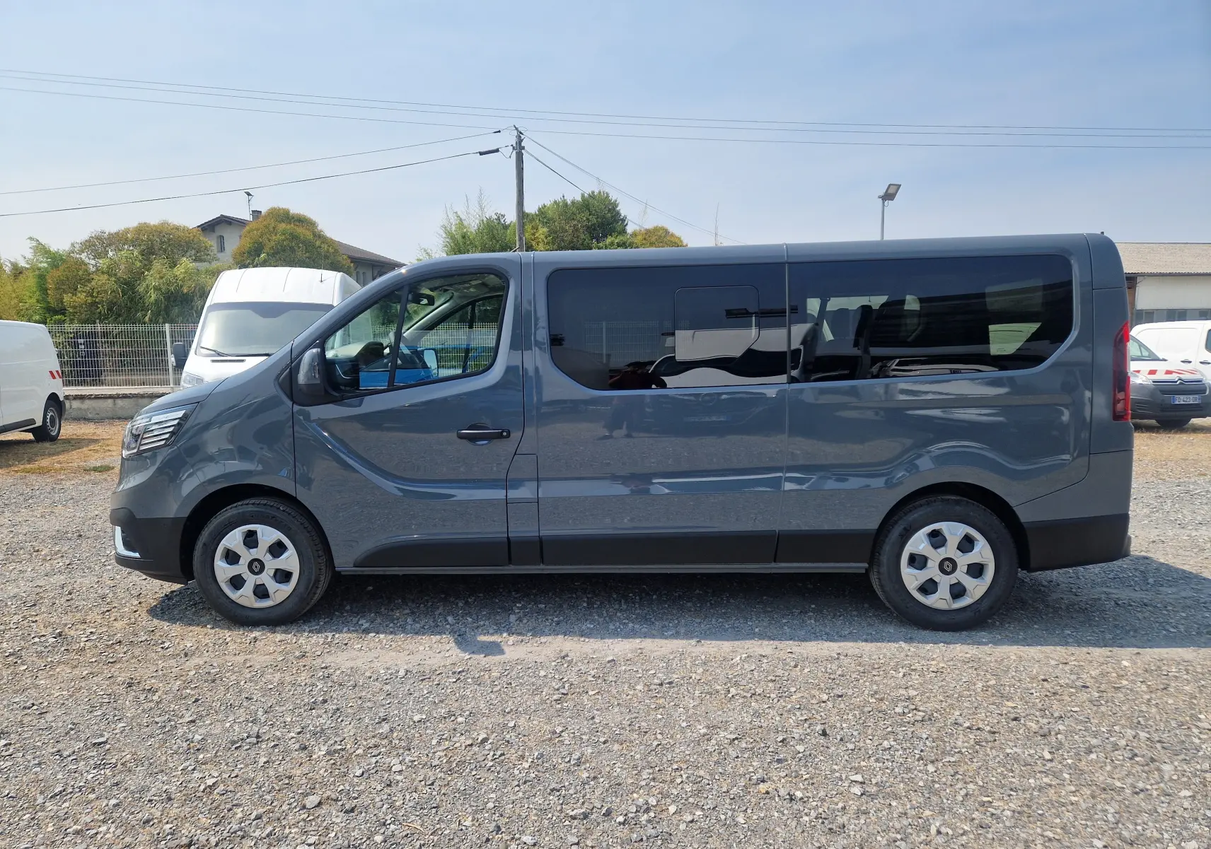 Profil côté gauche d’un Renault Trafic Combi gris urbain 2026, avec vitres teintées et porte coulissante visible.