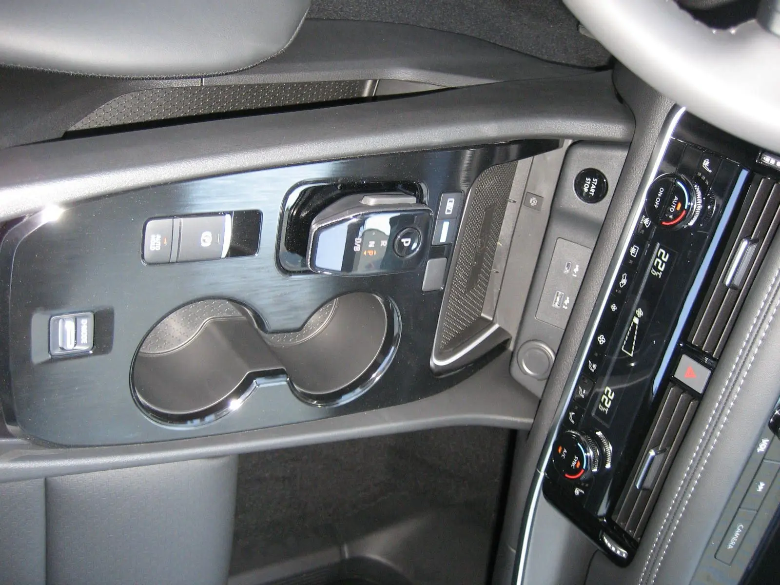 Vue rapprochée de la console centrale noire du Nissan X-TRAIL blanc nacré, avec commandes de boîte auto et climatisation digitale.