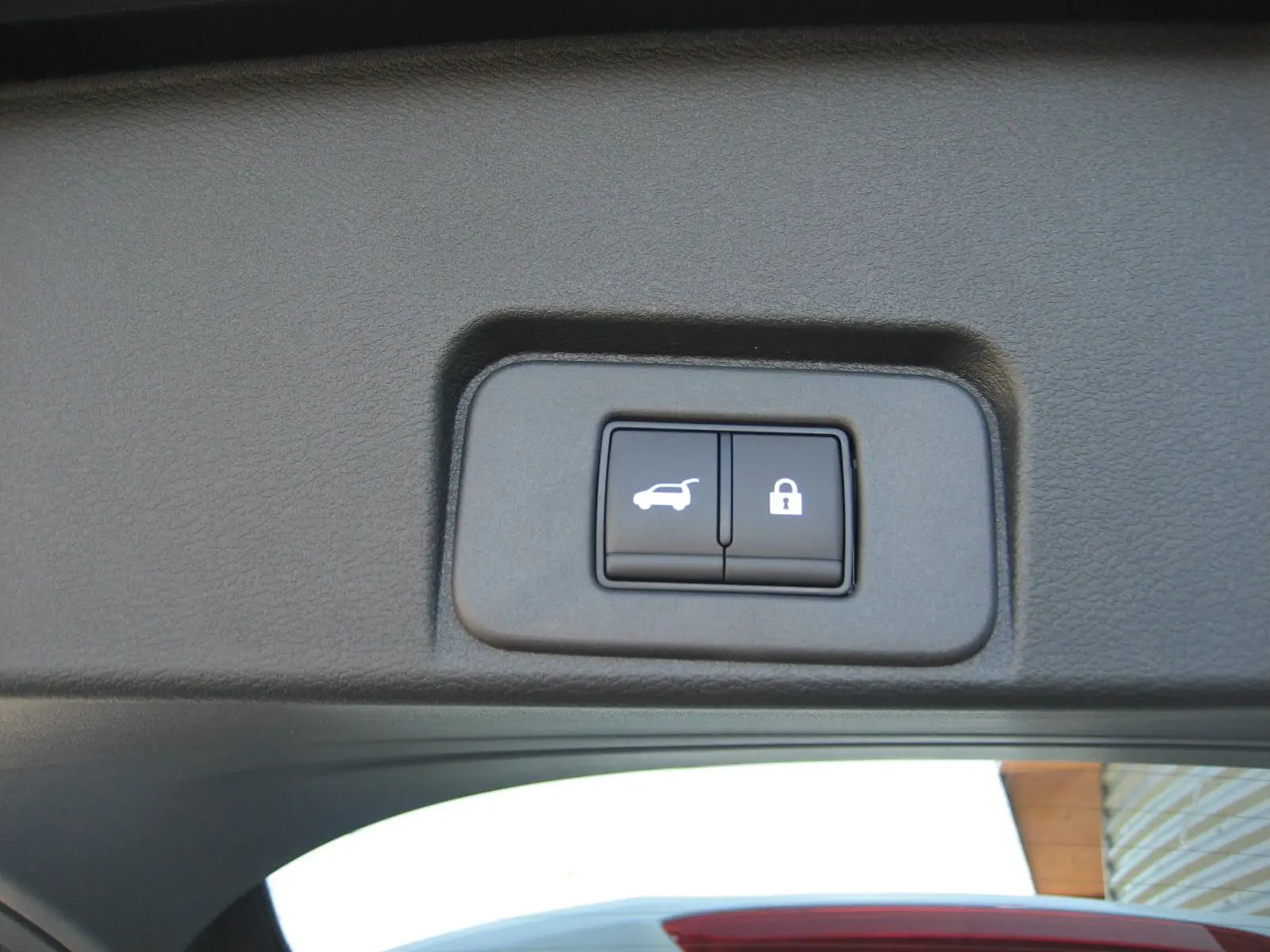 Boutons d'ouverture et de verrouillage du hayon sur la partie intérieure du coffre d'un Nissan X-TRAIL blanc nacré.
