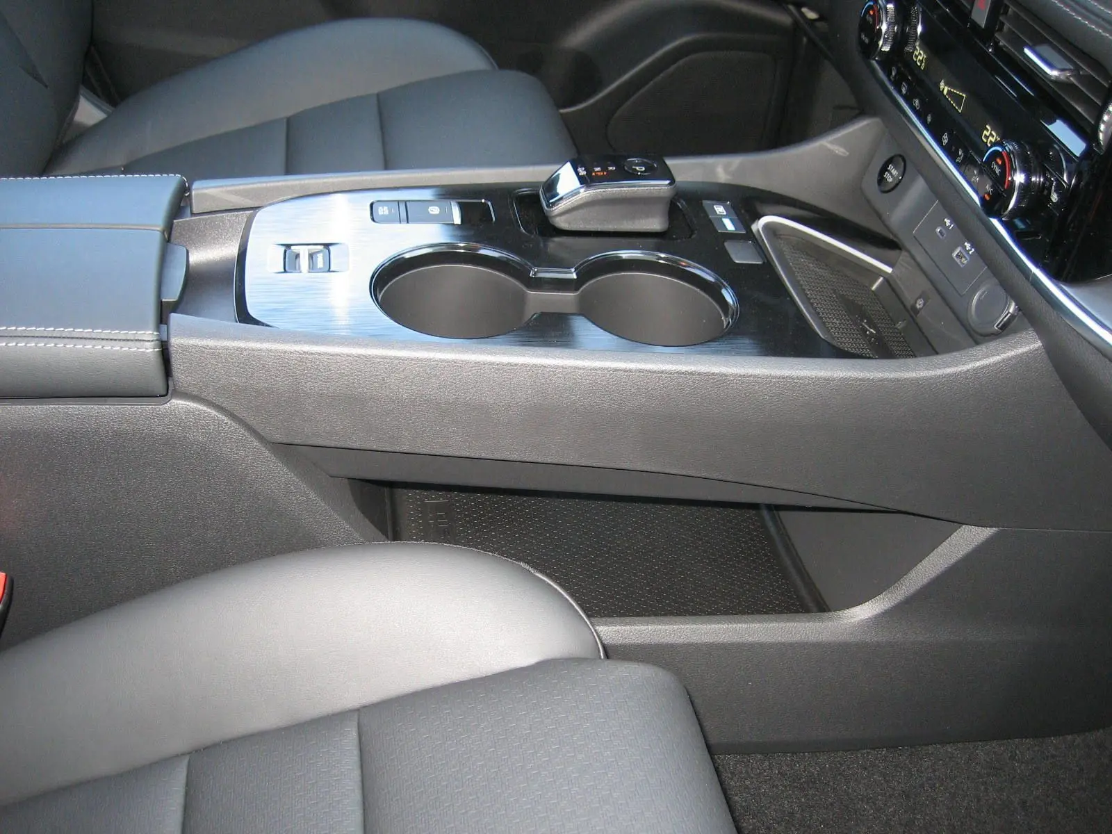 Gros plan sur la console centrale noire du Nissan X-Trail 2026, avec levier de vitesses et porte-gobelets.