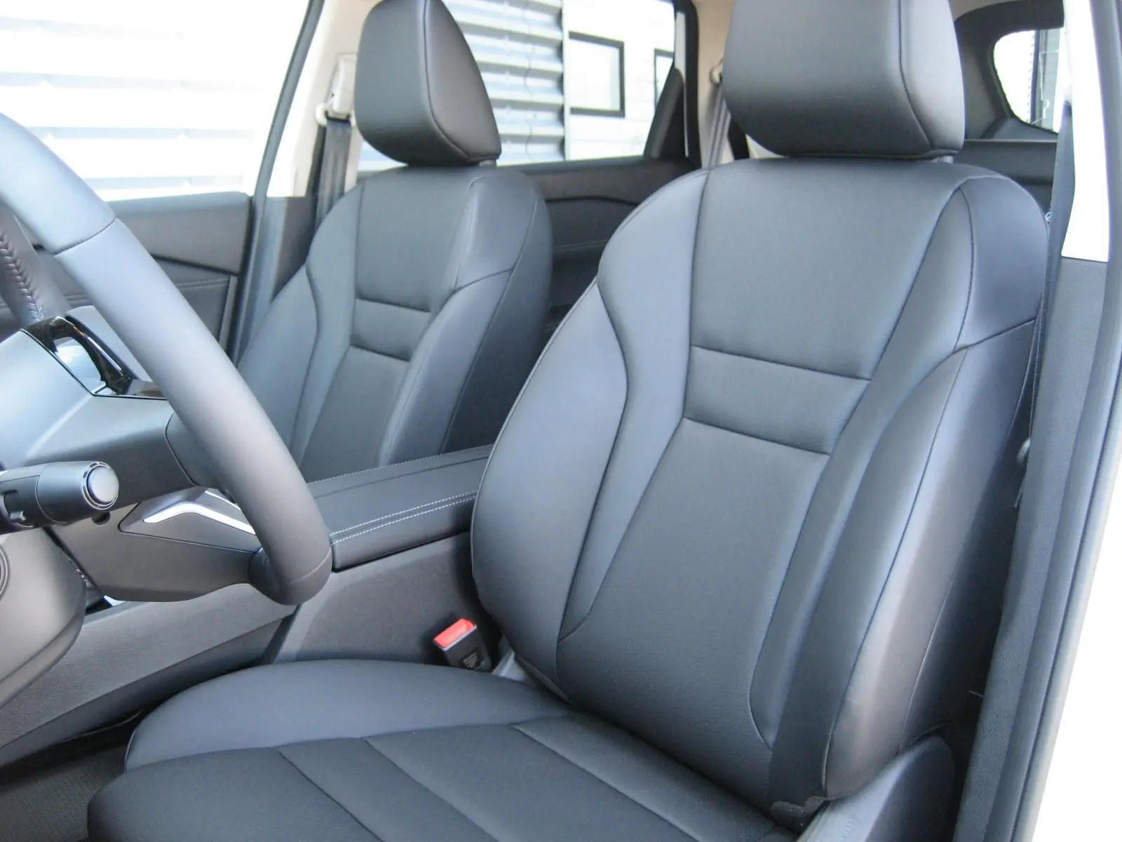Vue intérieure rapprochée des sièges avant en cuir noir du Nissan X-TRAIL blanc nacré, version 2026.