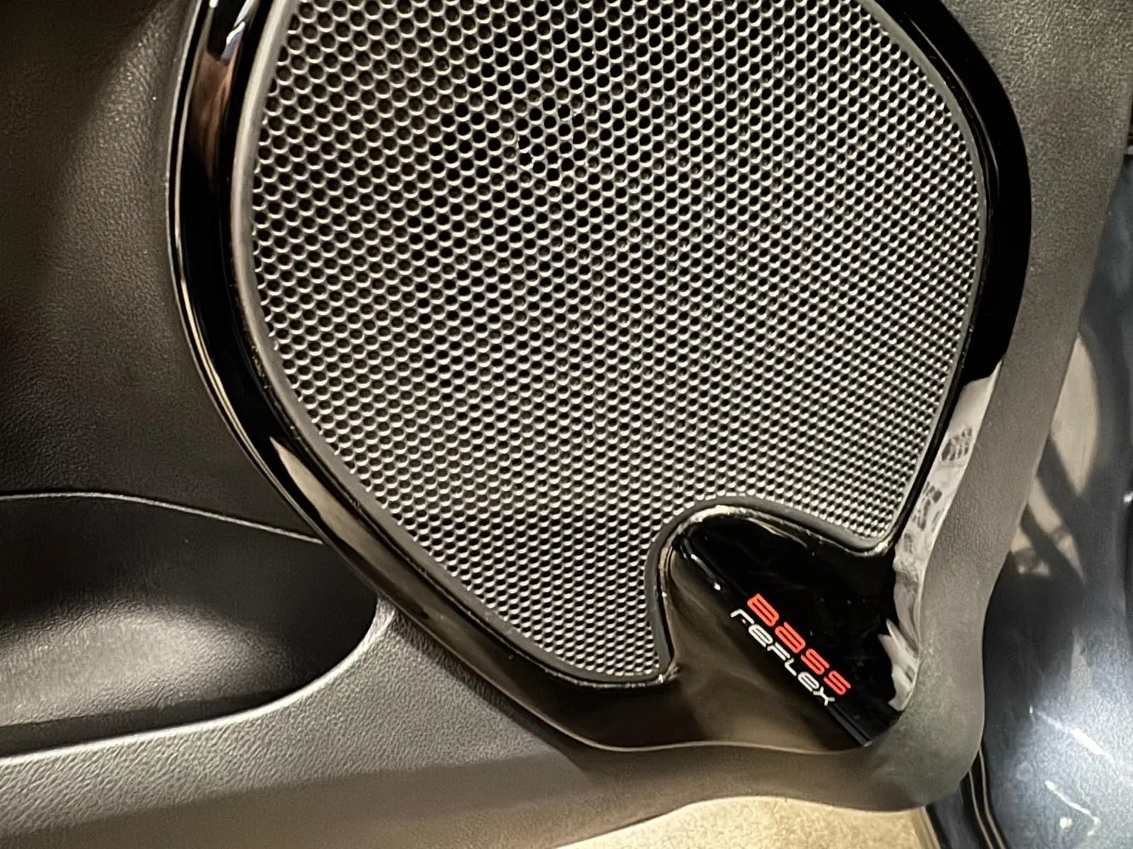 Gros plan sur l'enceinte Bose Reflex intégrée à la porte intérieure d'une Renault Clio IV gris foncé métal.