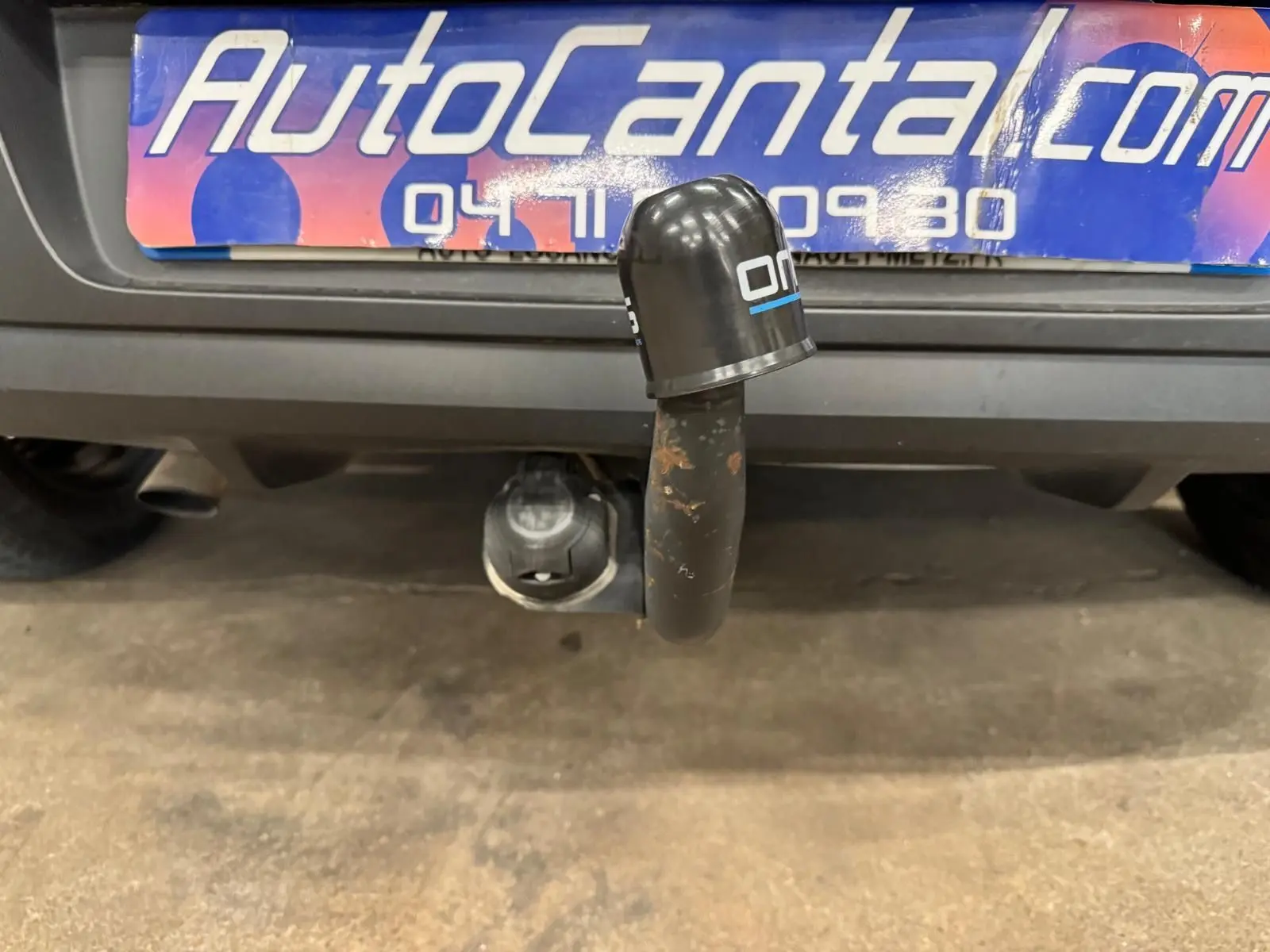 Gros plan sur l'attelage arrière d'une Renault Clio IV gris foncé, avec plaque d'immatriculation partiellement visible.