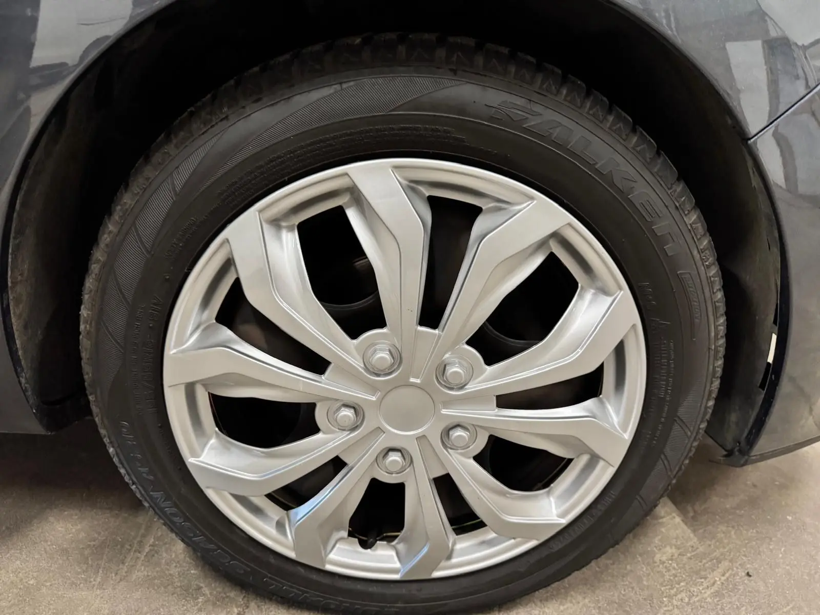 Gros plan sur la roue avant droite avec jante argentée de la Renault Clio IV gris foncé métallisé.