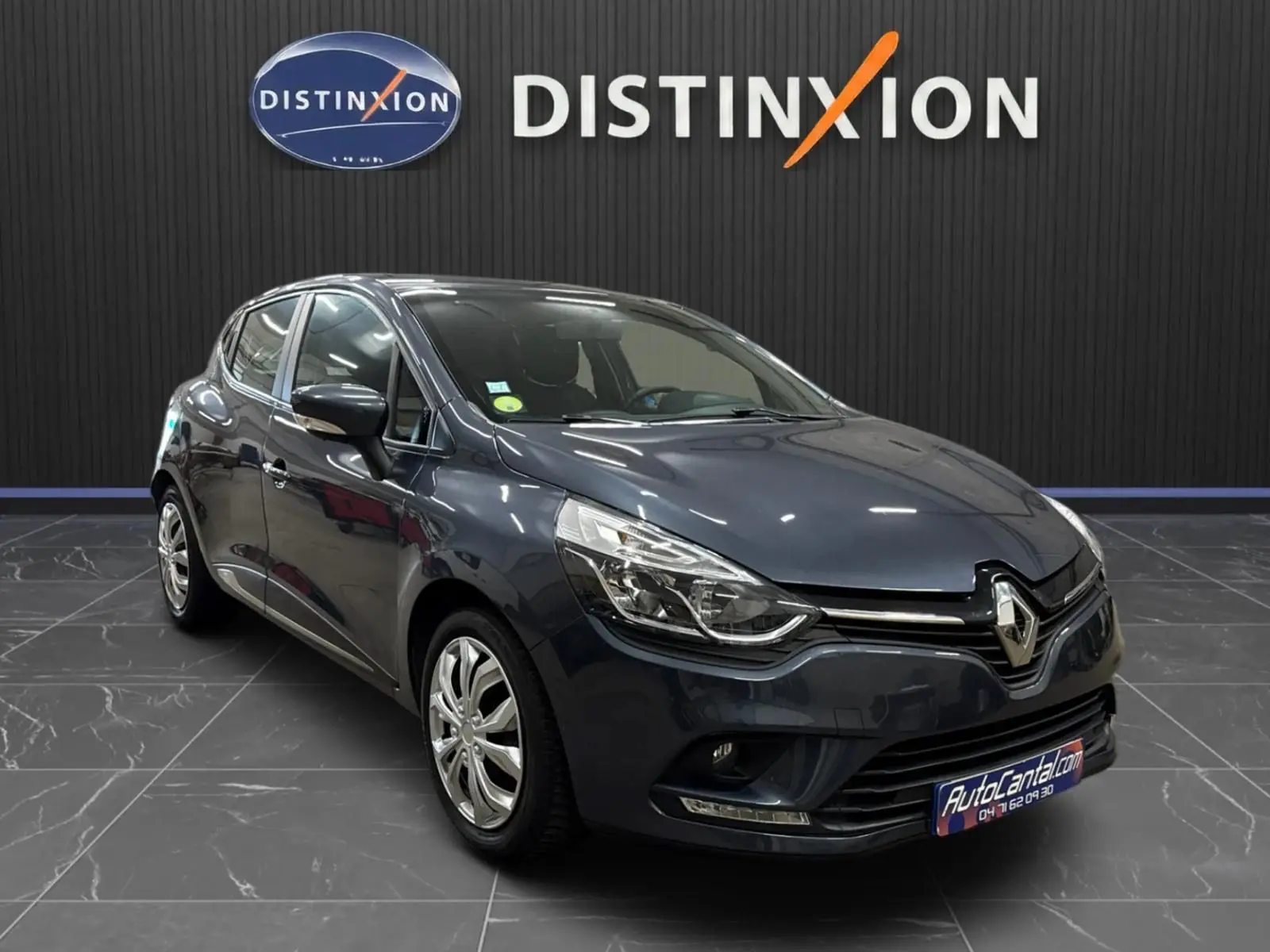 Renault Clio IV gris foncé métallisé vue 3/4 avant droit, avec phares LED et calandre chromée visible.