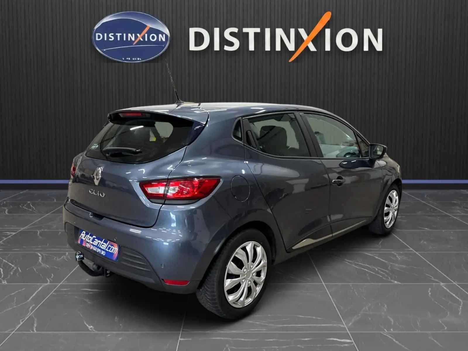 Renault Clio IV gris foncé métal vue 3/4 arrière droit avec attelage et jantes alliage en showroom.