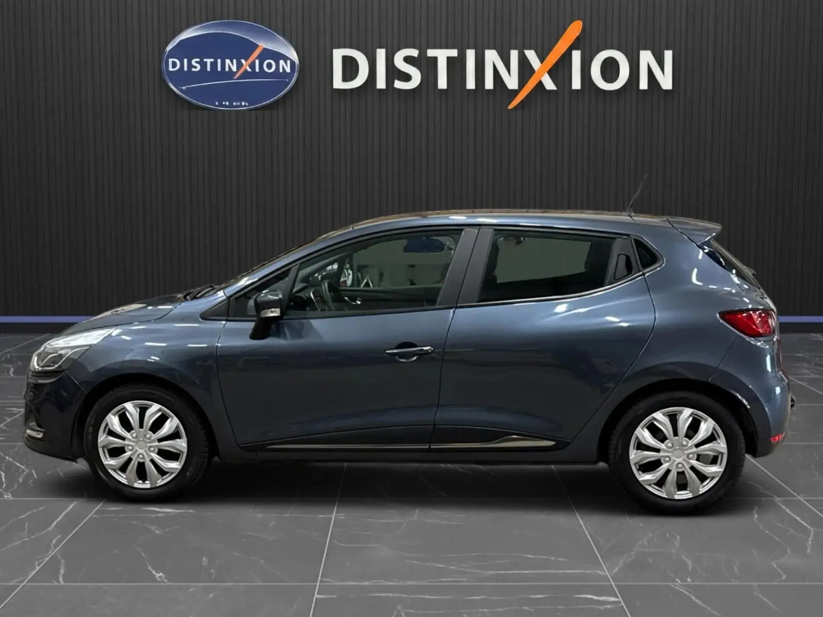 Renault Clio IV gris foncé métal vue de profil côté gauche, stationnée en intérieur avec jantes argentées.