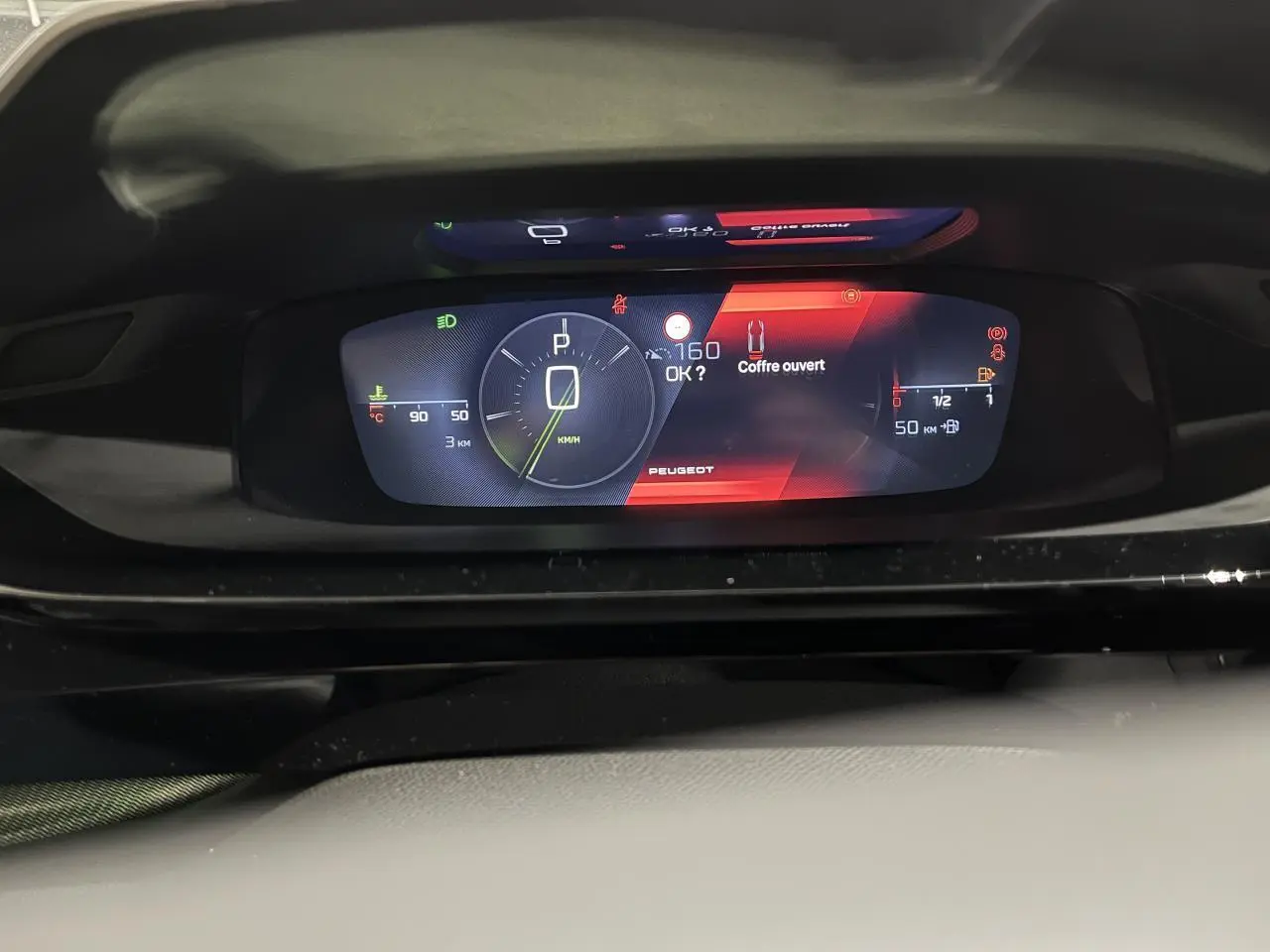 Tableau de bord numérique du Peugeot 308 GT 2024 affichant vitesse, jauge et alerte coffre ouvert.