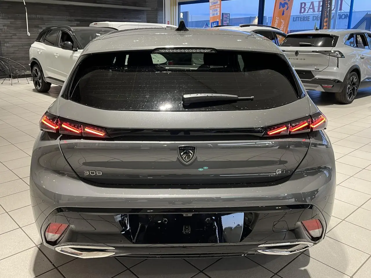 Vue arrière d'une Peugeot 308 GT gris selenium avec feux arrière LED griffés et double sortie d'échappement chromée.