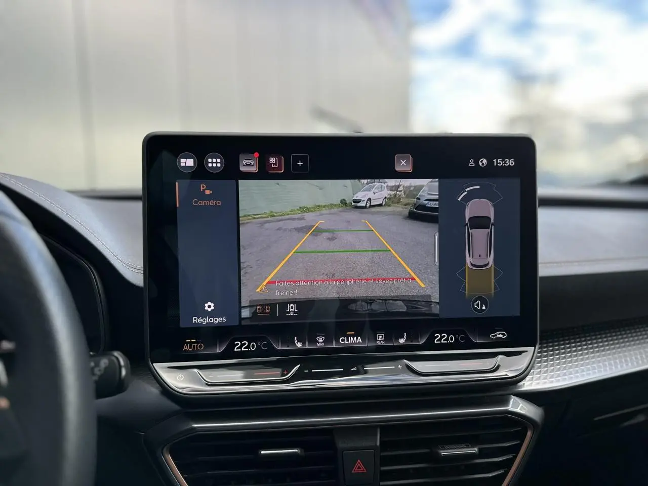 Écran tactile central affichant la caméra de recul d'un CUPRA Formentor blanc Neige, intérieur moderne avec tableau de bord noir.