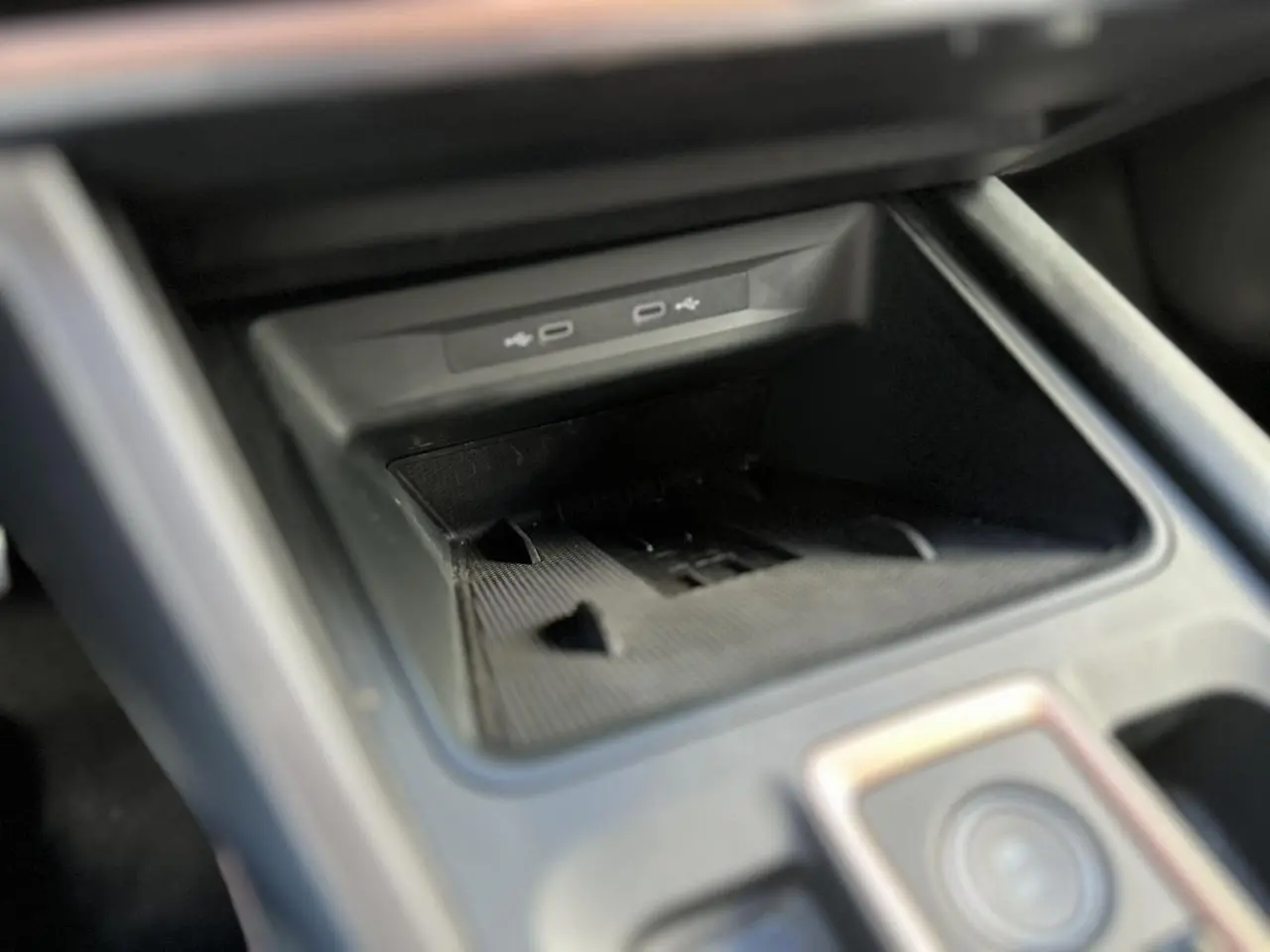 Gros plan sur la console centrale du CUPRA Formentor blanc Neige, montrant le compartiment de recharge avec ports USB.