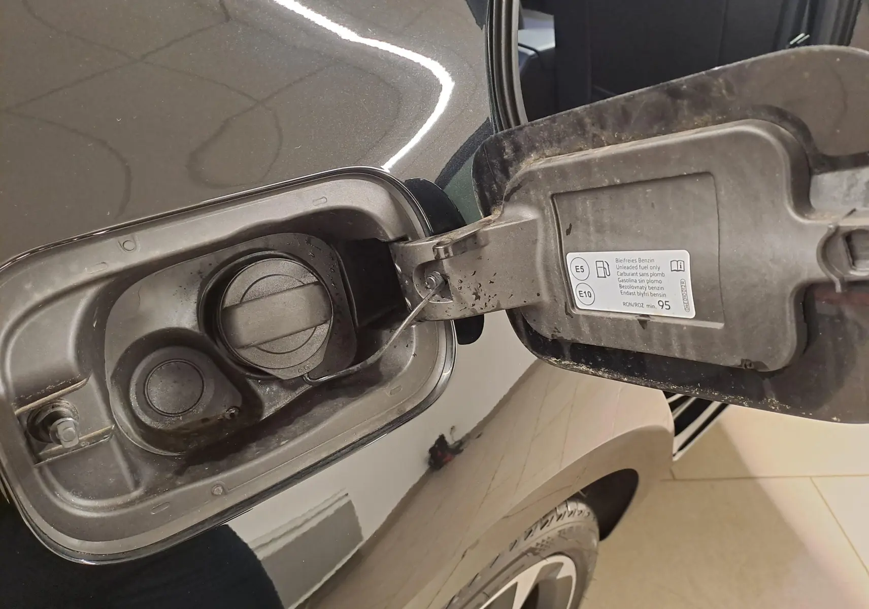 Gros plan sur la trappe de carburant ouverte côté gauche d'une CUPRA Leon 2023 noir minuit avec bouchon essence.