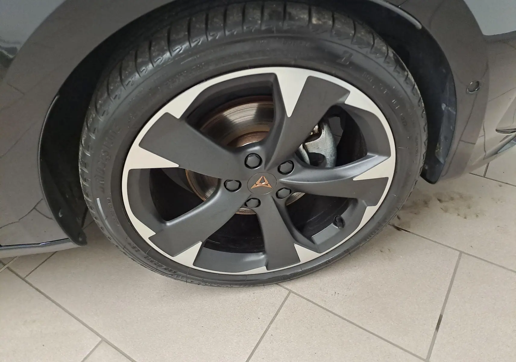 Gros plan sur la roue avant droite de la CUPRA Leon 2023 noir minuit, mettant en valeur la jante noire et argentée au design distinctif.