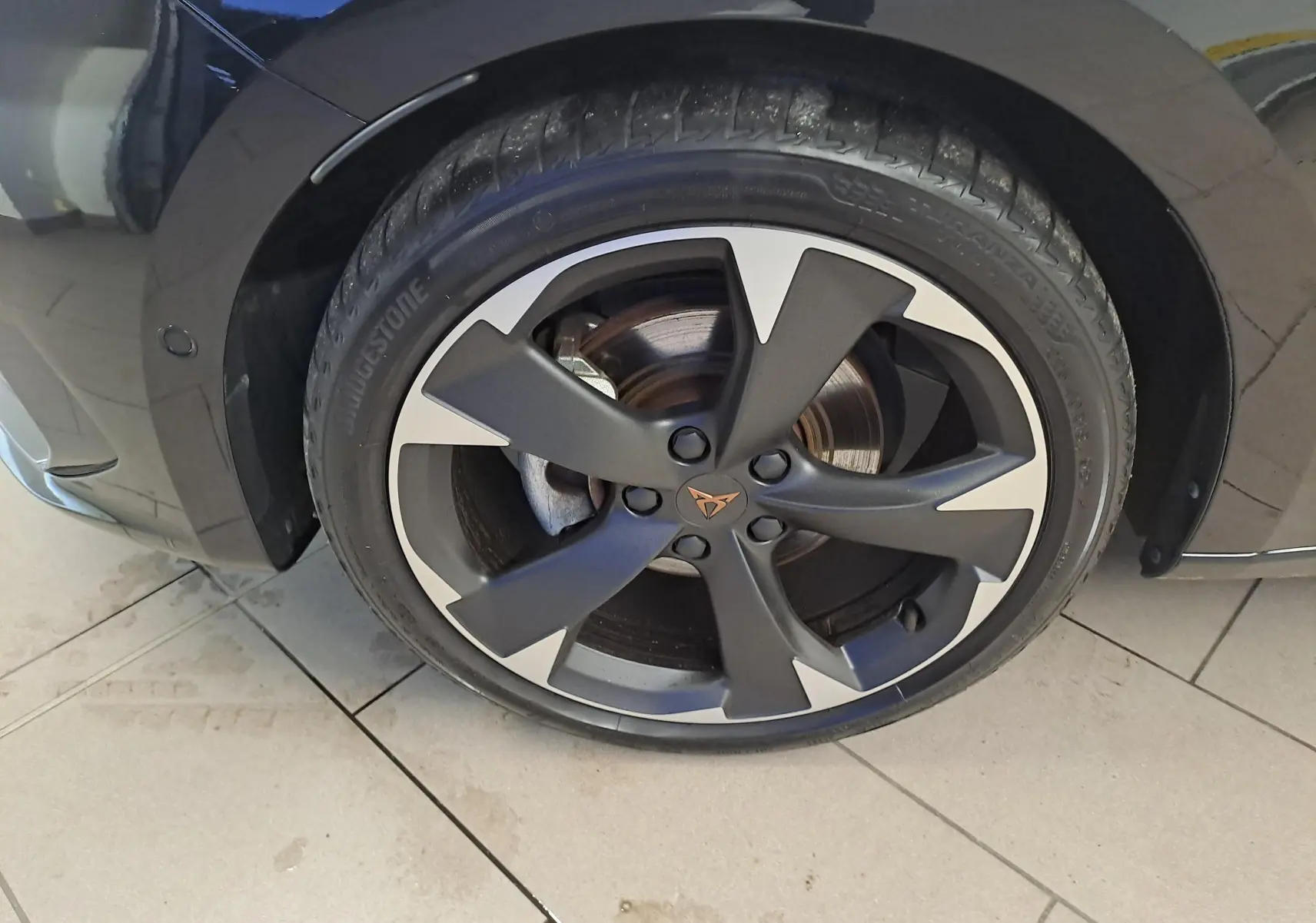 Gros plan sur la roue avant gauche d'une CUPRA Leon 2023 noire Minuit avec jante alliage noire et argentée au design distinctif.