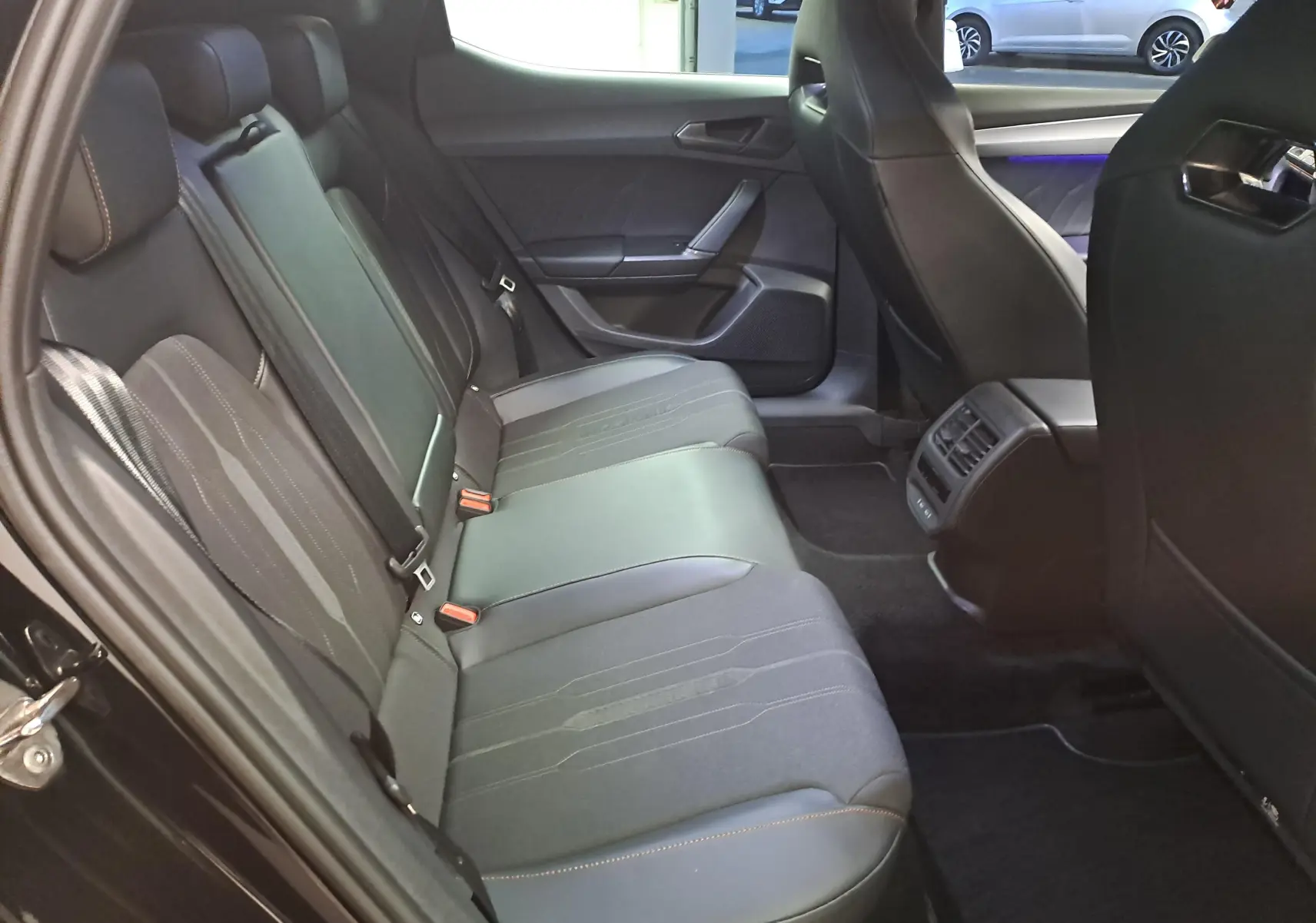 Vue intérieure côté gauche des sièges arrière noirs avec surpiqûres orange dans une CUPRA Leon 2023 Noir Minuit.