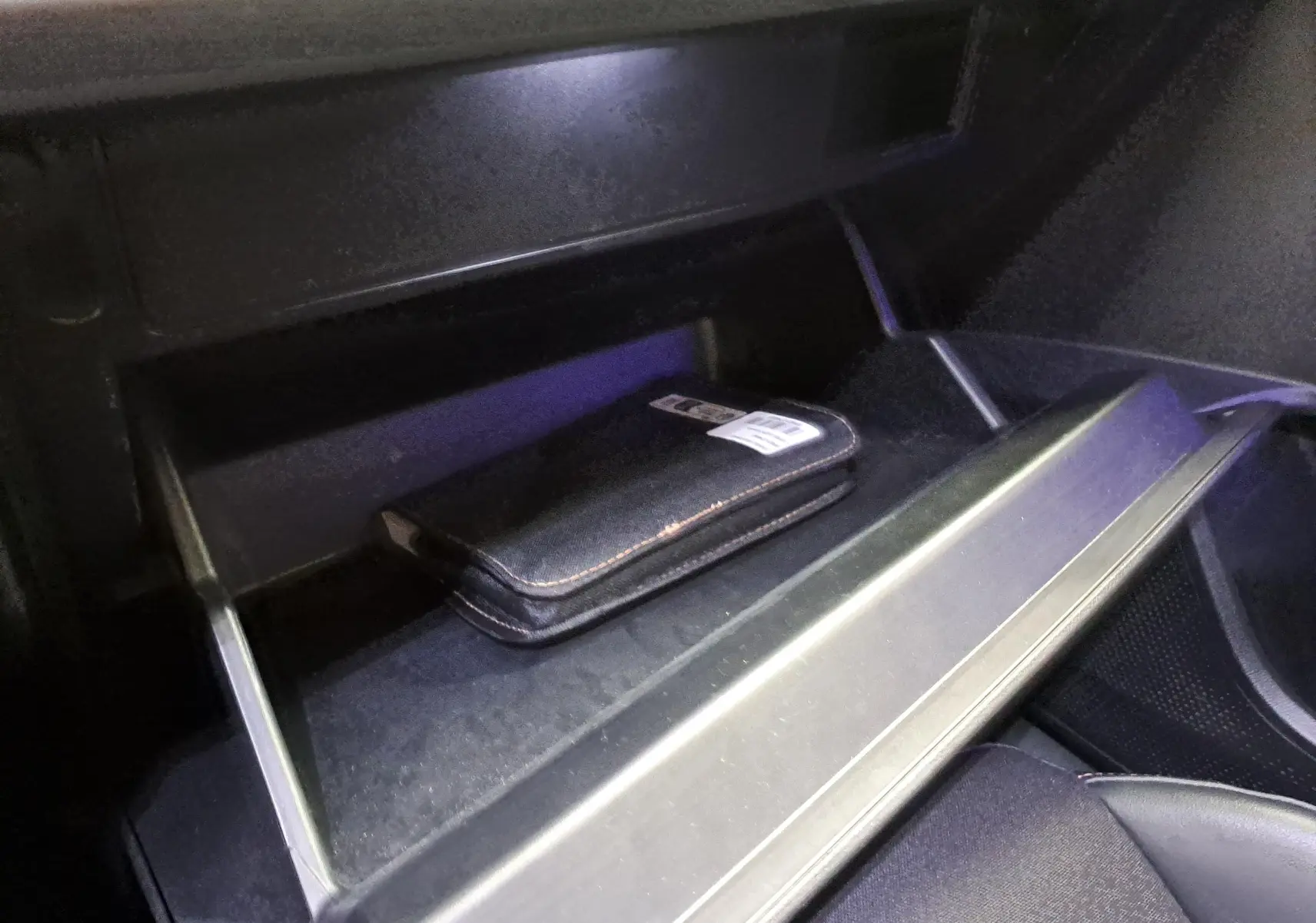 Gros plan sur la boîte à gants ouverte de la CUPRA Leon 2023 noir minuit avec un étui noir à l'intérieur.