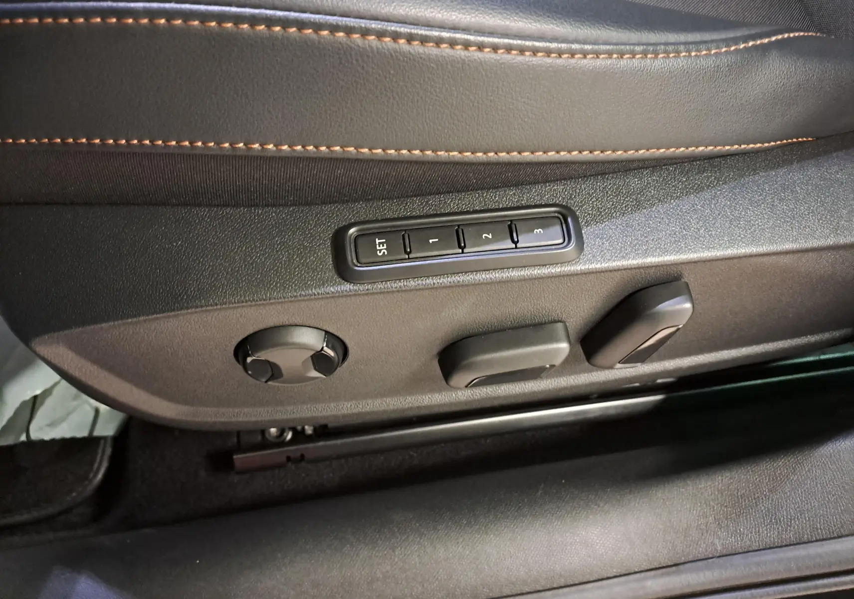Gros plan sur les commandes de réglage électrique du siège conducteur en cuir noir avec surpiqûres orange dans une CUPRA Leon 2023.