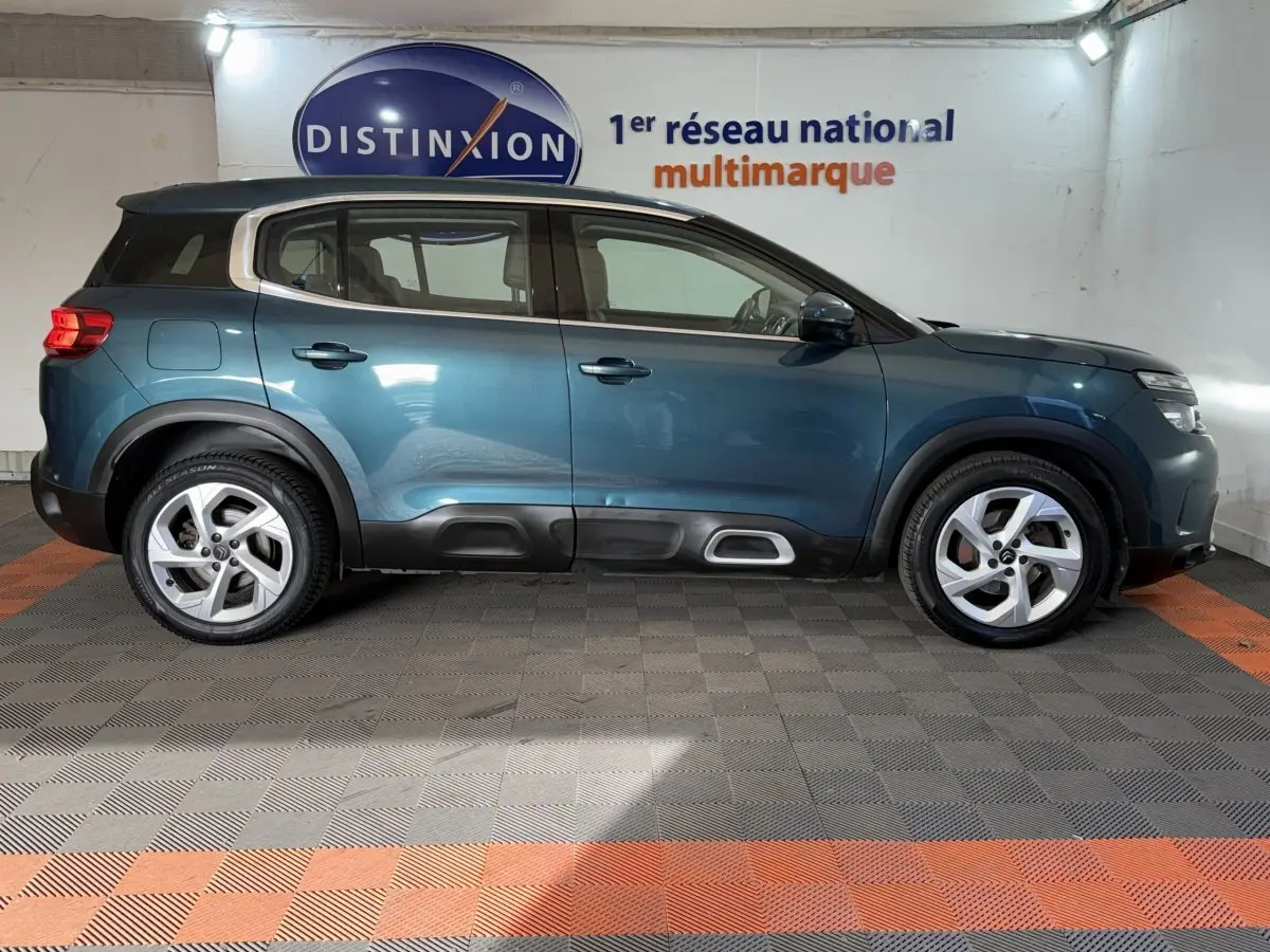 Profil latéral droit d'un Citroën C5 Aircross bleu 2021 avec toit noir et protections de bas de caisse noires.