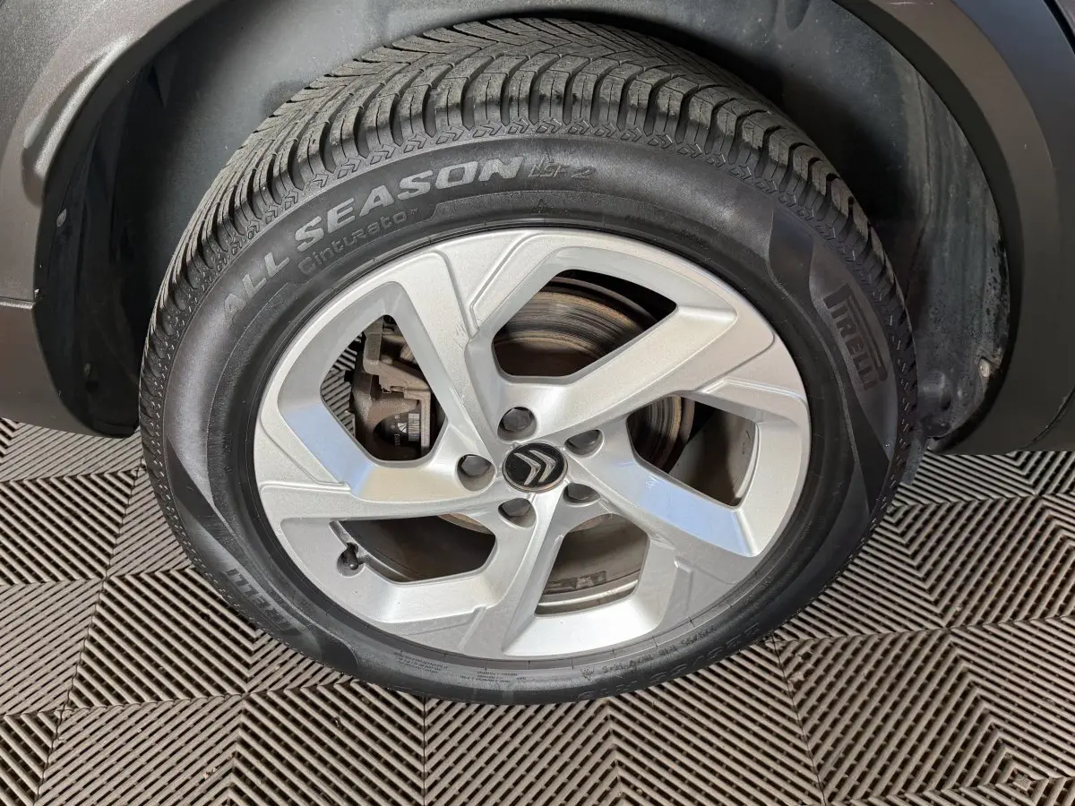 Gros plan sur la roue avant droite avec jante argentée et logo Citroën sur un C5 Aircross bleu.