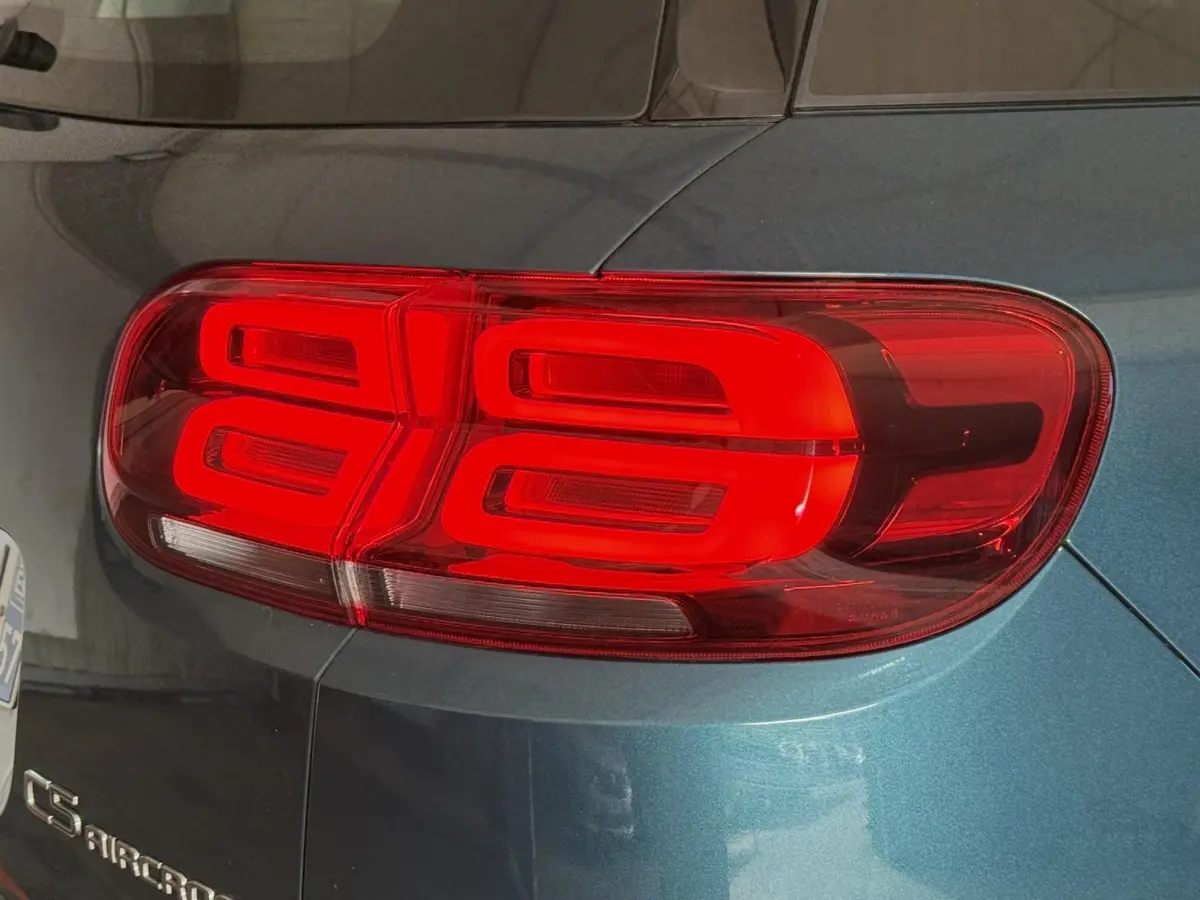 Gros plan sur le feu arrière droit rouge du Citroën C5 Aircross bleu métallisé, avec logo visible sur la carrosserie.
