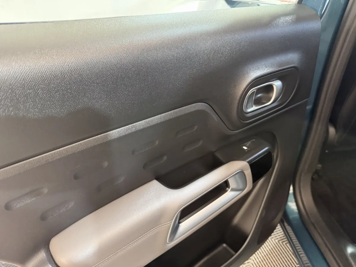 Vue rapprochée de la porte avant gauche bleu foncé du Citroën C5 Aircross avec poignée argentée et commande de vitre.