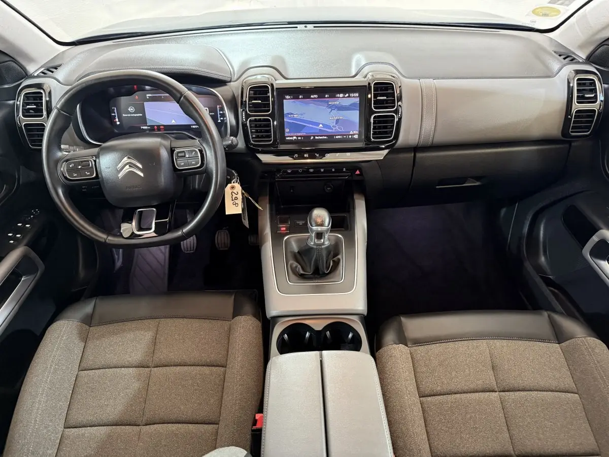 Vue intérieure avant du Citroën C5 Aircross bleu, montrant le volant cuir multifonctions et l’écran tactile central.