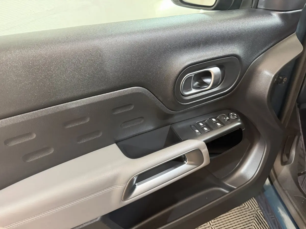 Gros plan sur la porte avant gauche bleu foncé du Citroën C5 Aircross avec commandes de vitres et poignée argentée.
