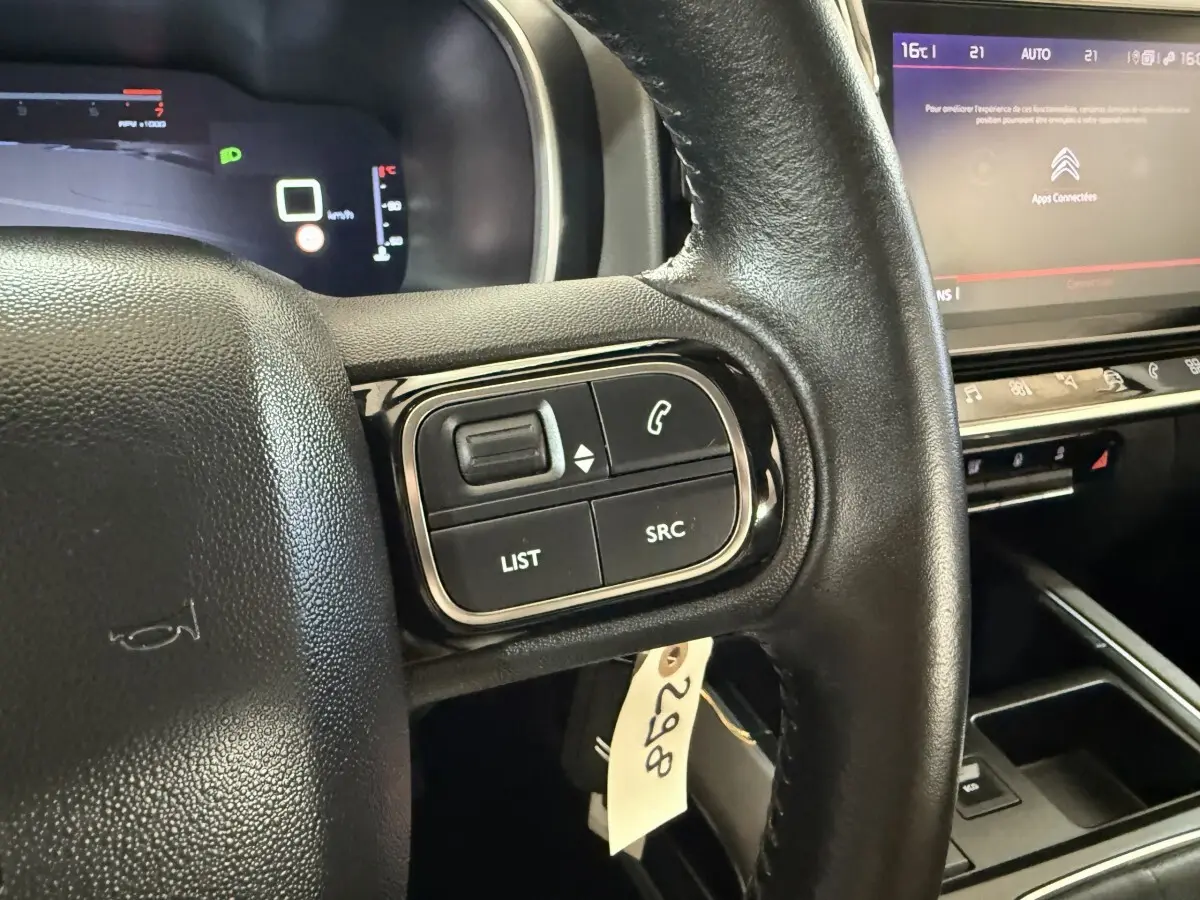 Gros plan sur le volant cuir multifonctions côté gauche du Citroën C5 Aircross avec tableau de bord numérique en arrière-plan.