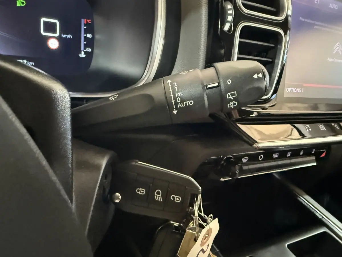 Gros plan sur la commande d'essuie-glace et la clé insérée dans le tableau de bord noir du Citroën C5 Aircross bleu.